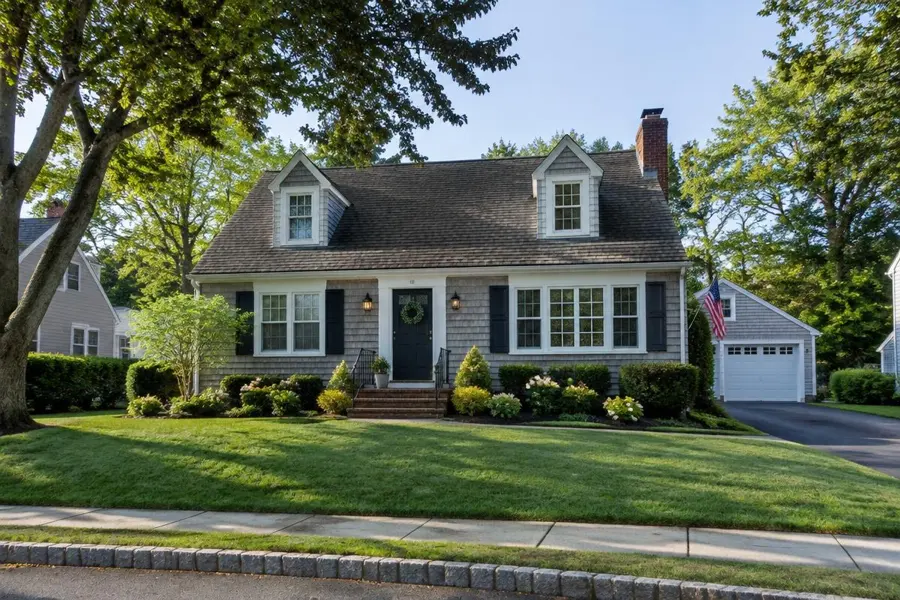 Cedar-shingle Cape Cod home with a well-kept green front lawn in Kenilworth, NJ
