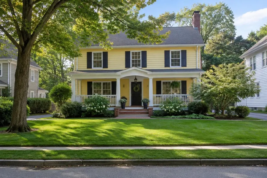 Yellow colonial home with a front porch and a thick established lawn in Cranford, NJ