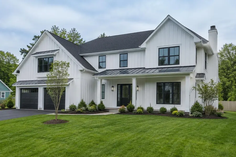 Newly built white board-and-batten farmhouse with black windows, fresh sod and young plantings in Chatham, NJ