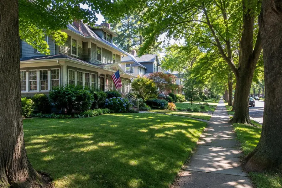 Front lawns shaded by large street trees along a sidewalk in Cranford, NJ