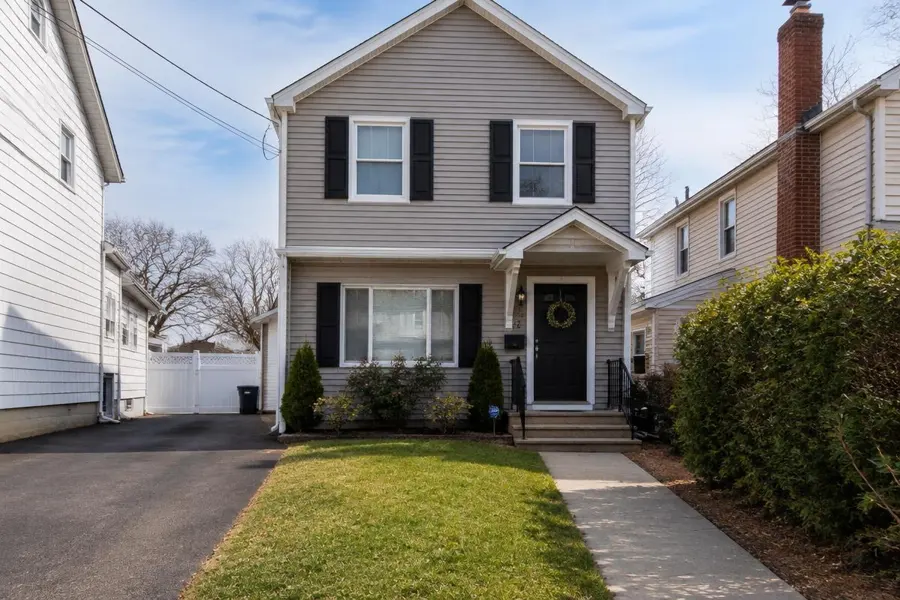 Compact two-story home with a narrow front lawn between the driveway and walkway in Kenilworth, NJ