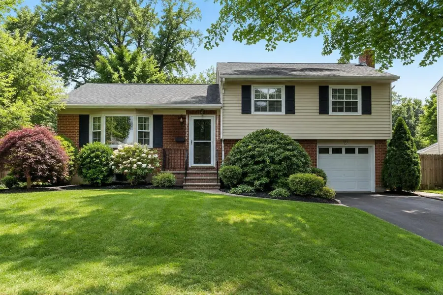 Split-level home with an established green front lawn and mature shrubs in Springfield, NJ
