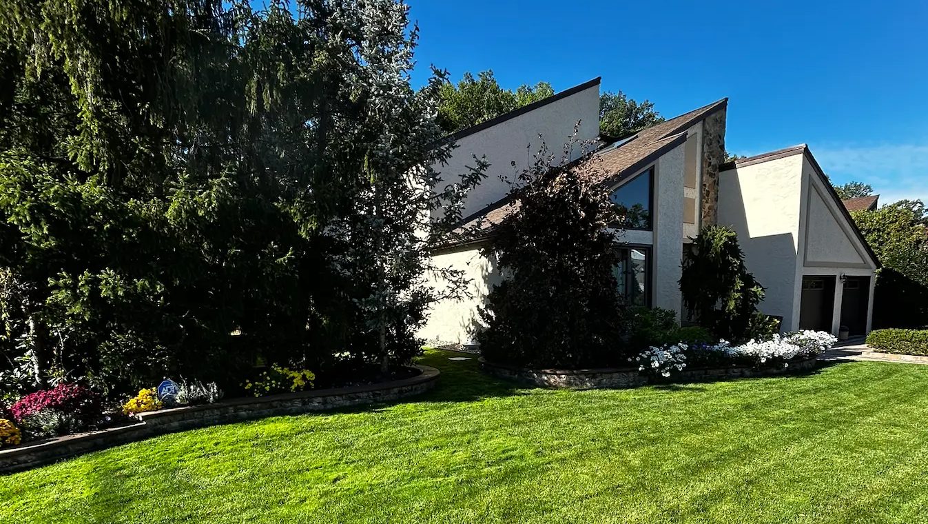 Contemporary home with a thick, freshly striped front lawn, mature evergreens and flower beds in Springfield, NJ