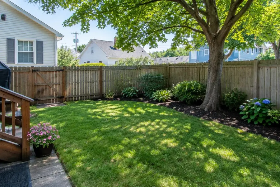 Small fenced backyard lawn with a shade tree and hydrangea bed in Garwood, NJ