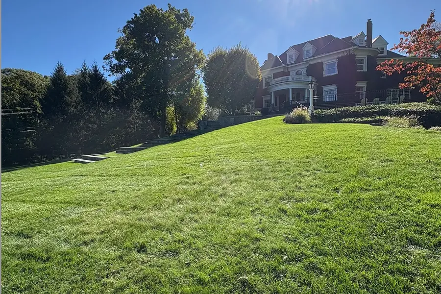 Sloping green lawn with stone steps rising to a historic ivy-covered home in Summit, NJ
