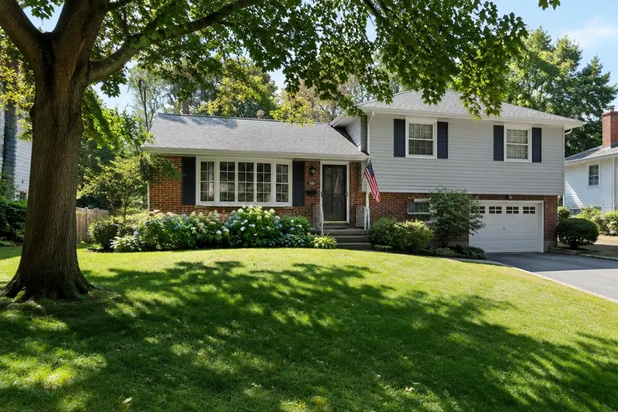 Split-level home with a front lawn partly in sun and partly in shade from a large tree in Scotch Plains, NJ