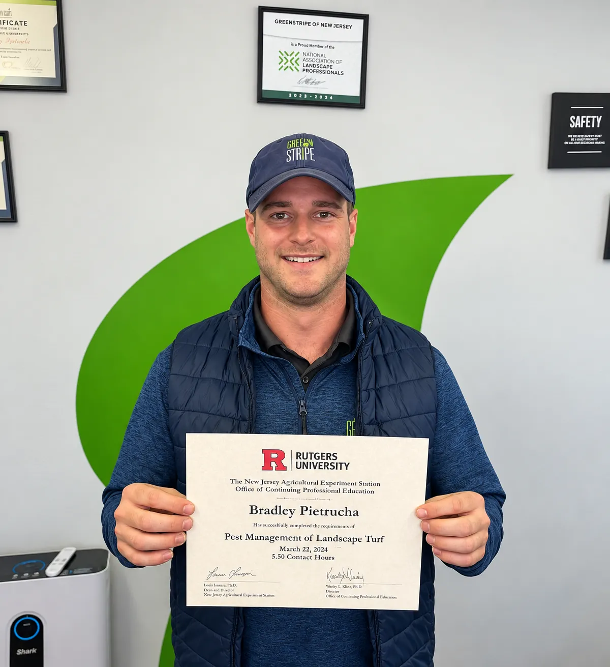GreenStripe team member Bradley holding his Rutgers Pest Management of Landscape Turf certificate