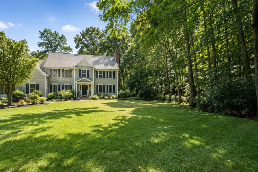Sunny open lawn meeting a shaded wooded edge beside a colonial home in Mountainside, NJ
