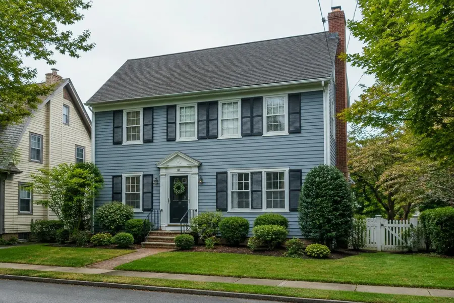 Established blue colonial home with foundation plantings and a tidy small lawn in Garwood, NJ