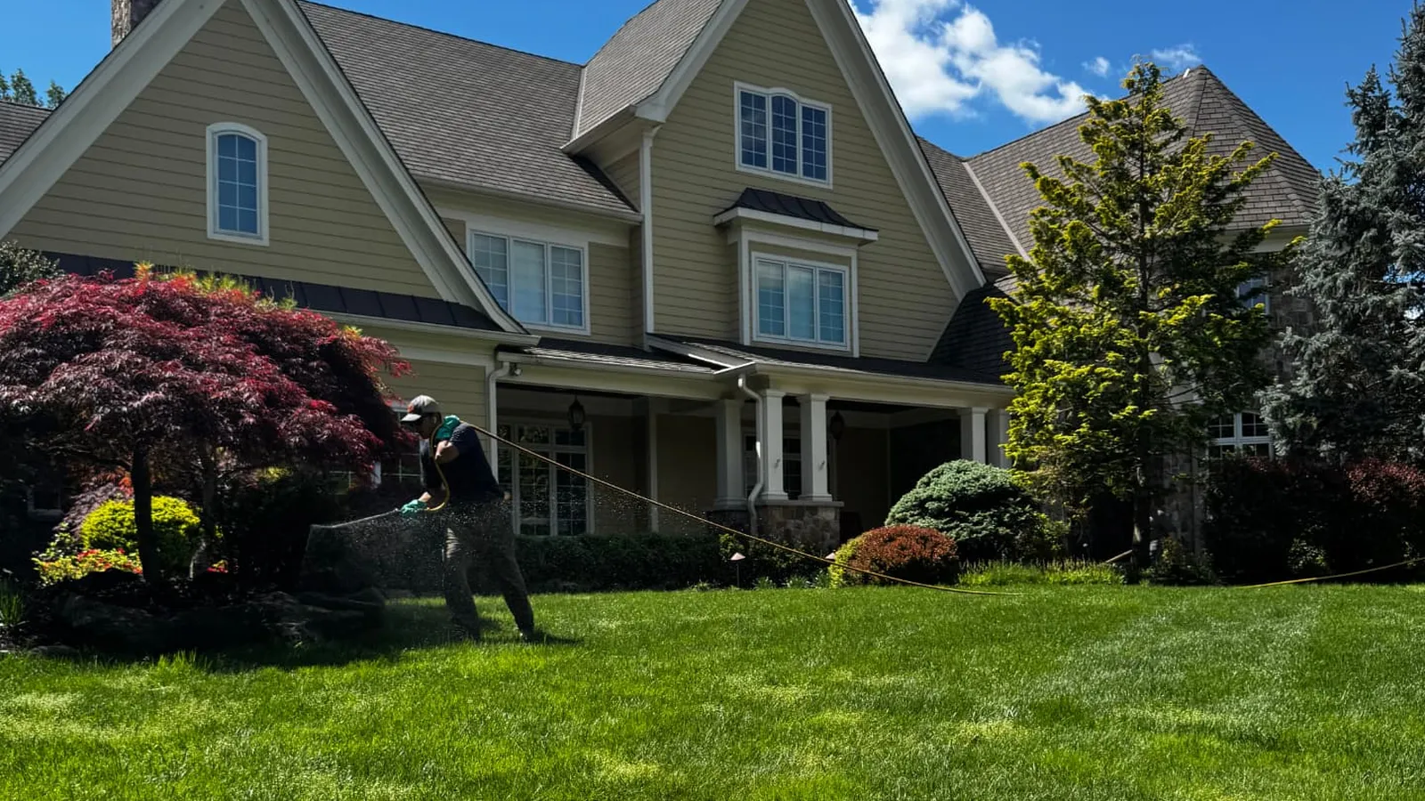 GreenStripe technician treating a thick front lawn at a large home in Scotch Plains, NJ