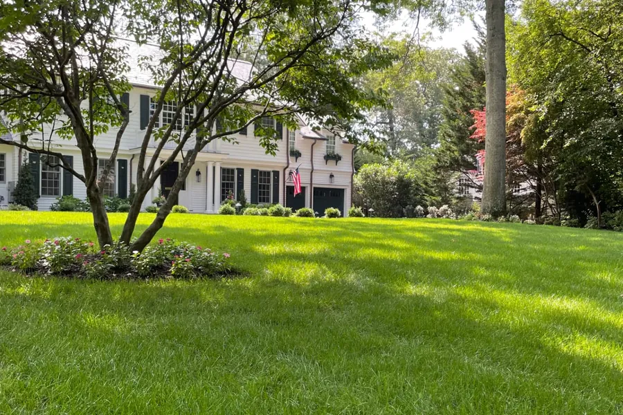 White colonial home with a thick, healthy front lawn and mature trees in Northern New Jersey