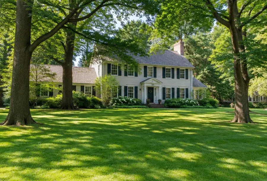 Established colonial home set back behind a wide lawn shaded by large old trees in Millburn, NJ