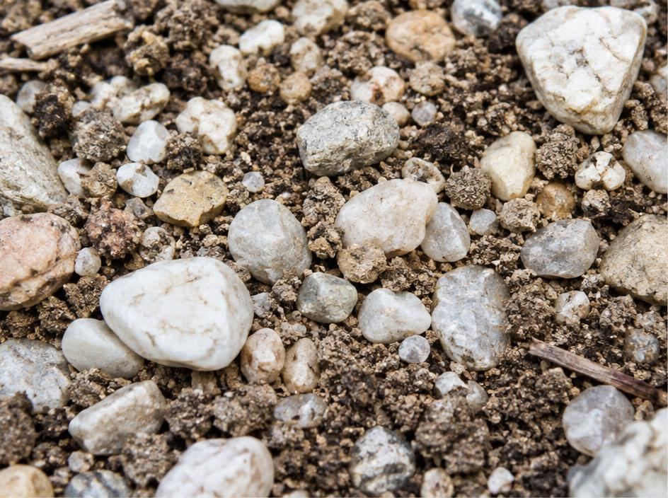 Closeup of mineral pebbles mixed through light soil