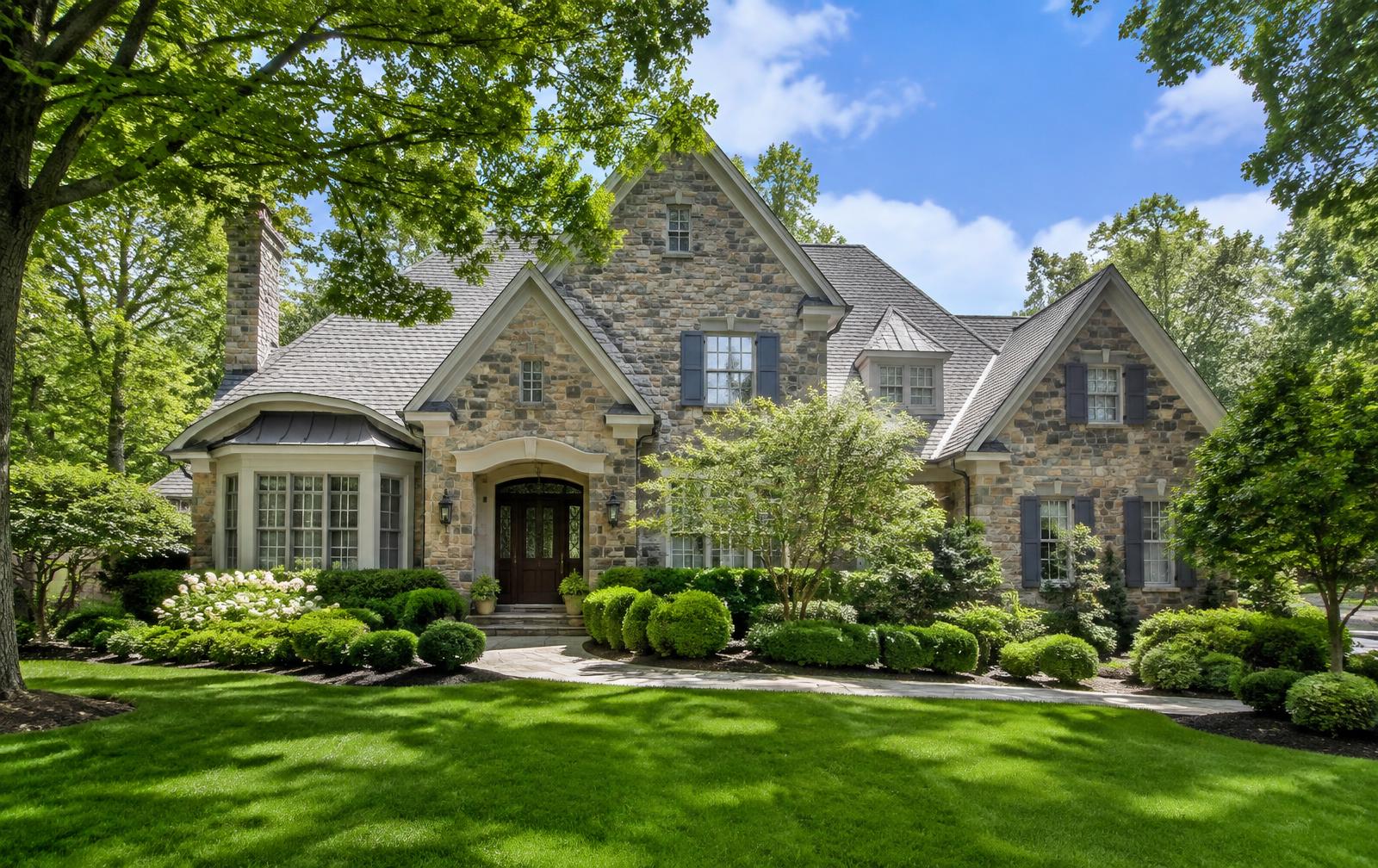Stone Northern New Jersey home framed by manicured ornamental shrubs and mature shade trees